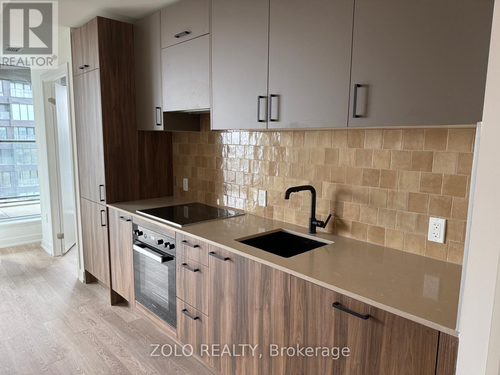 A kitchen with wooden cabinets and a tiled backsplash.