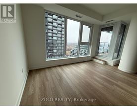 A room with wooden flooring and large windows overlooking a cityscape.
