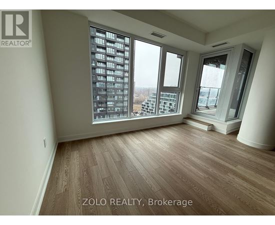 A room with wooden flooring and large windows overlooking a cityscape.