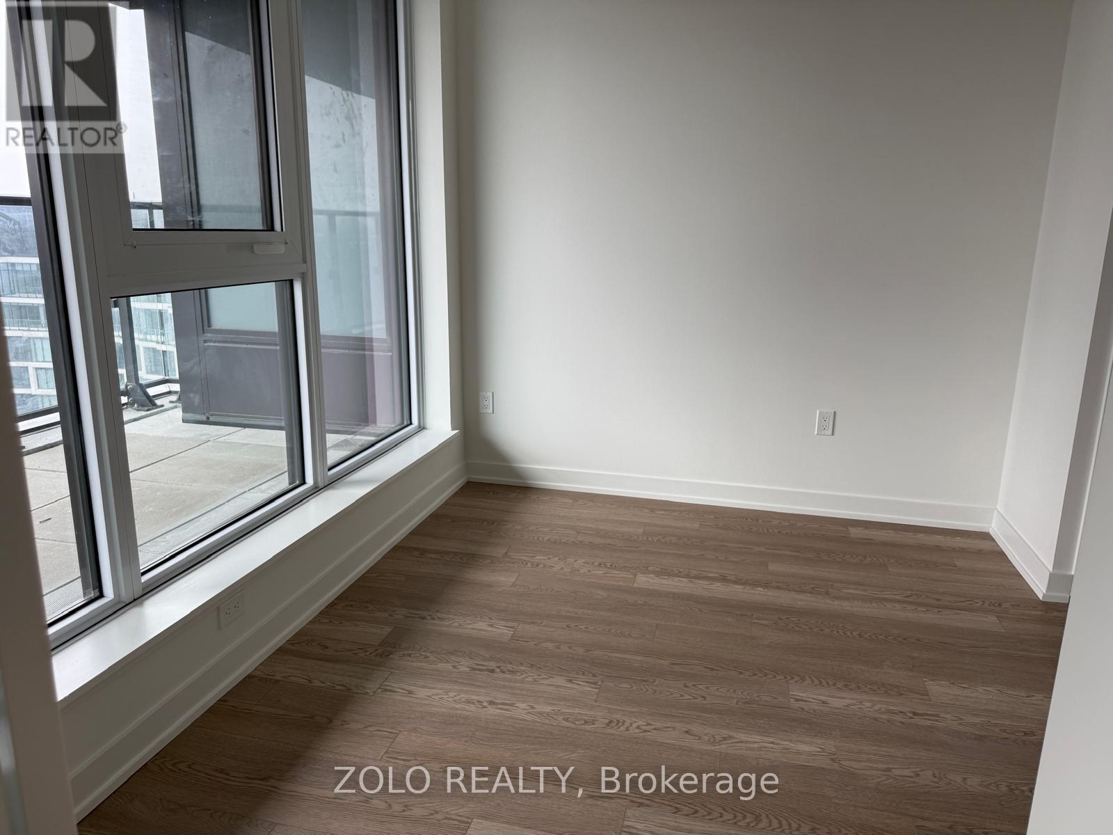 A room with a large window and wooden flooring.