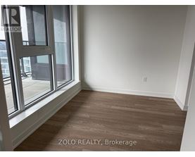 A room with a large window and wooden flooring.