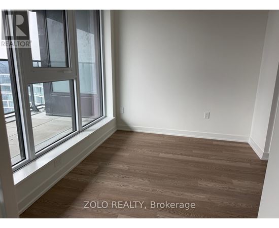 A room with a large window and wooden flooring.