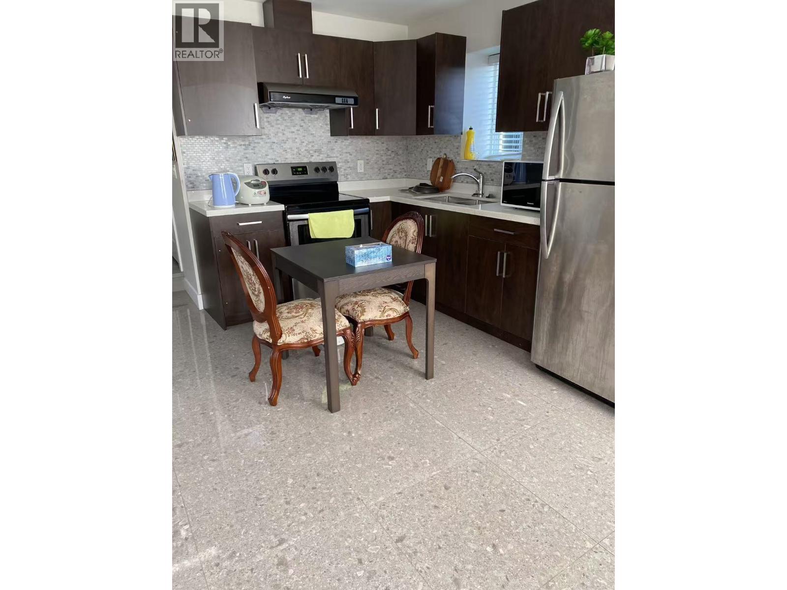 A kitchen with a table and chairs.