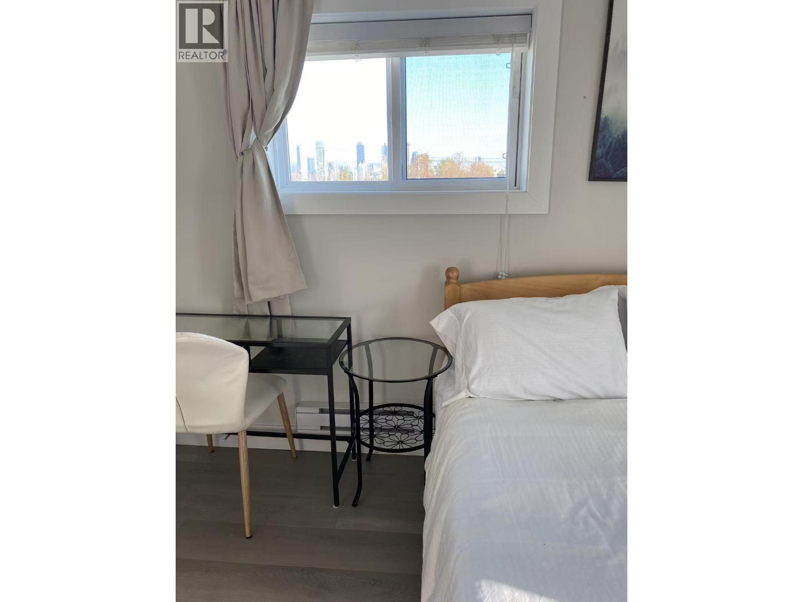 A bedroom with a bed, chair, and table.
