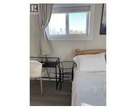 A bedroom with a bed, chair, and table.