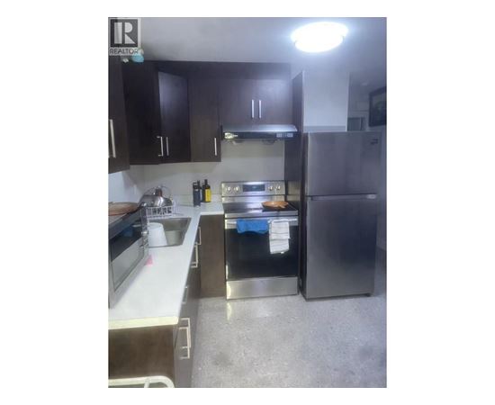 A kitchen with a sink, stove, and refrigerator.