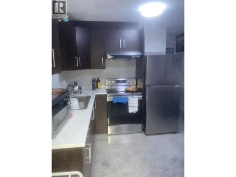 A kitchen with a sink, stove, and refrigerator.