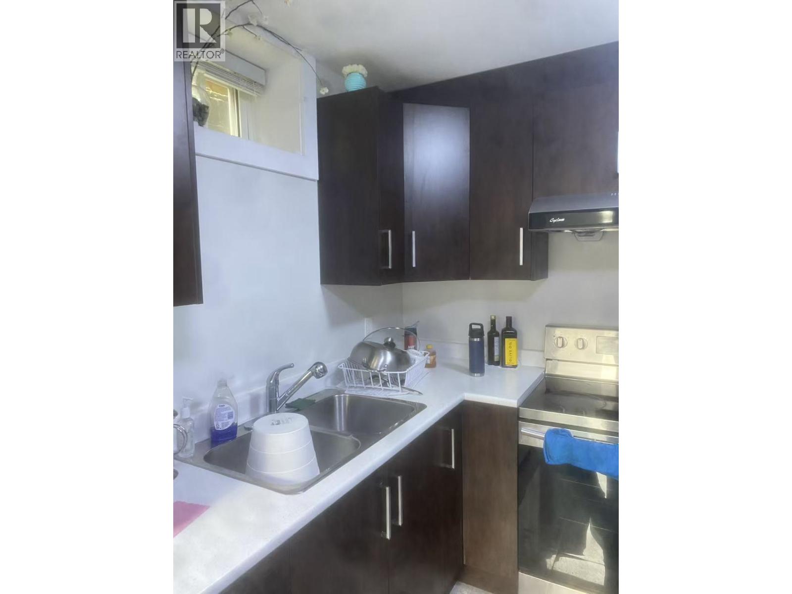 A kitchen with a sink, stove, and cabinets.