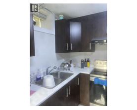 A kitchen with a sink, stove, and cabinets.