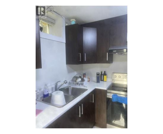 A kitchen with a sink, stove, and cabinets.