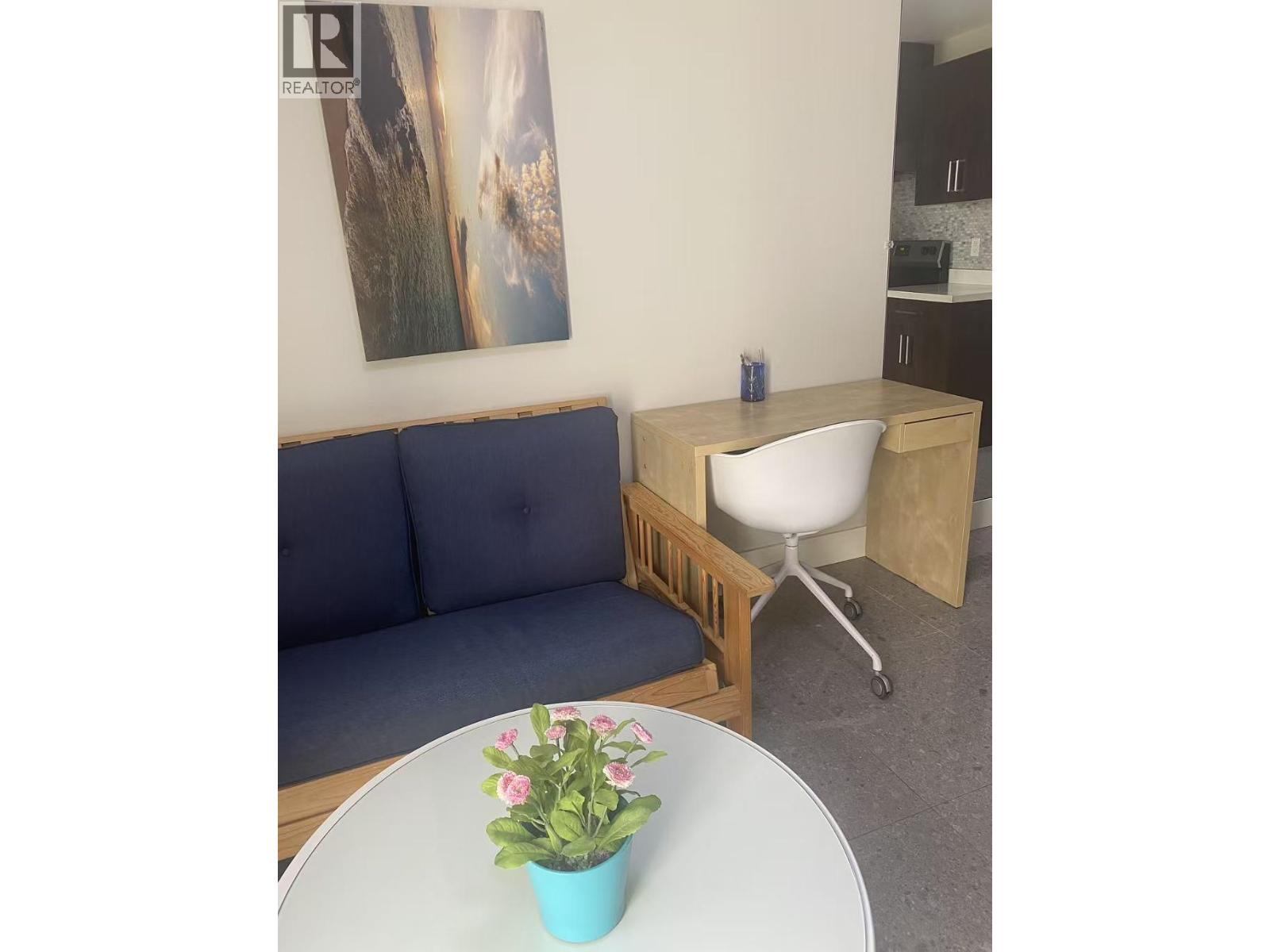 A blue couch sits in a room with a white table in front of it.