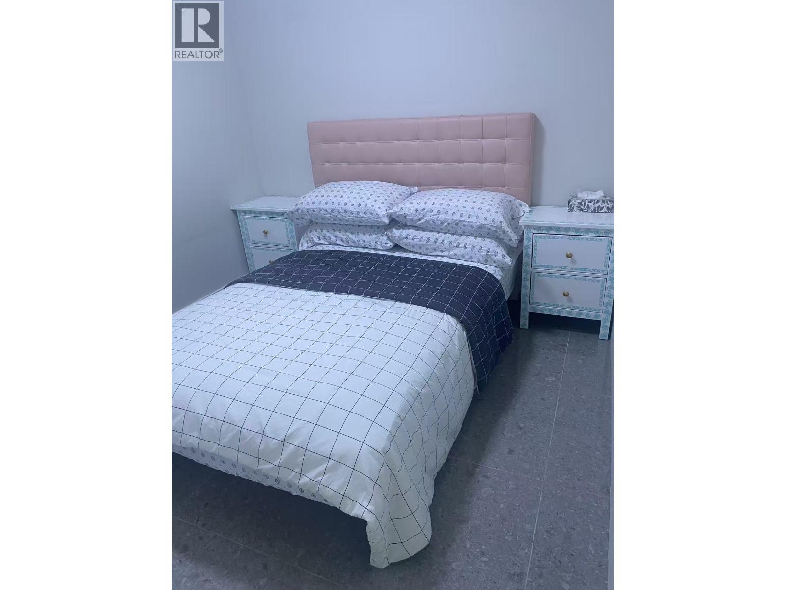 A bed with a pink headboard and a white bedspread with a blue patterned duvet.