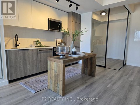 A modern kitchen with a wooden table and a microwave above the sink.