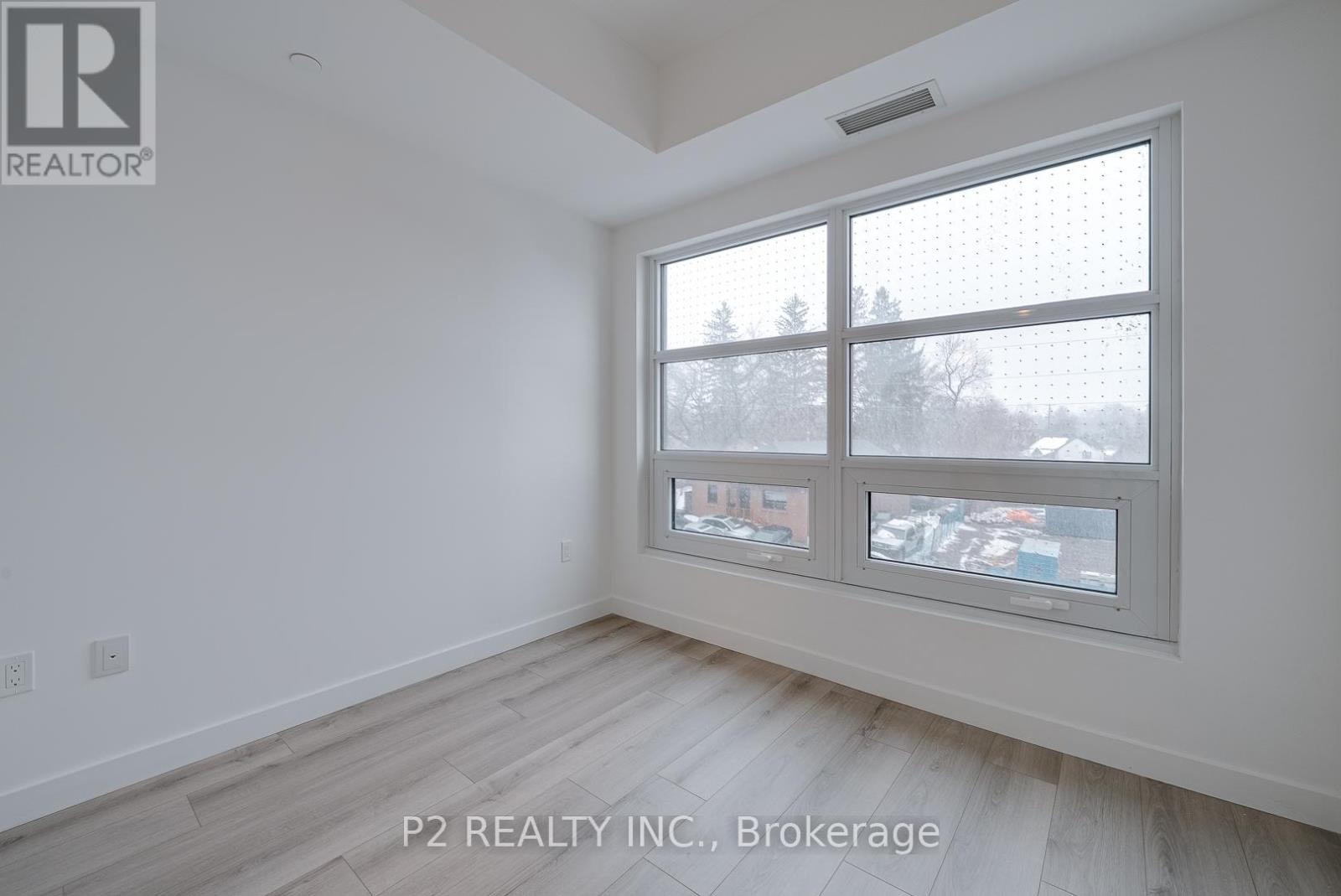 A room with a window showing a view of trees and buildings outside.