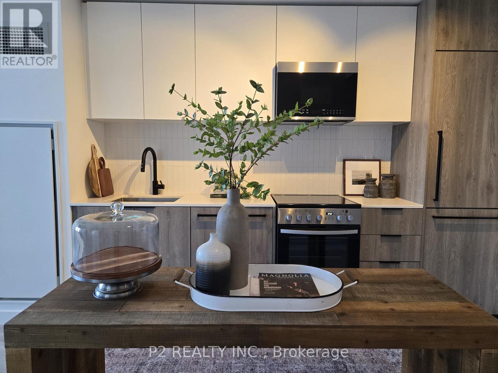 A kitchen with a wooden table in the foreground and a plant on it.