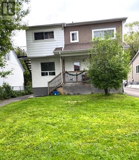 A house with a white and brown exterior and a green lawn.