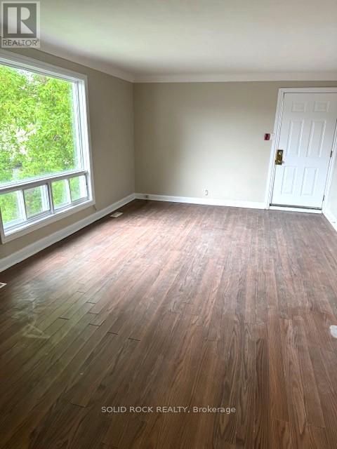 A room with a white door and a window with a view of trees.