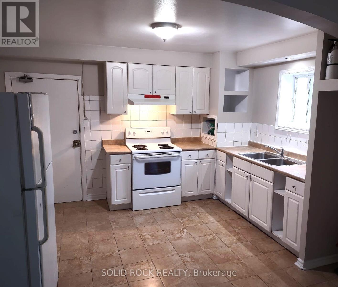 A kitchen with white cabinets and a tiled backsplash.