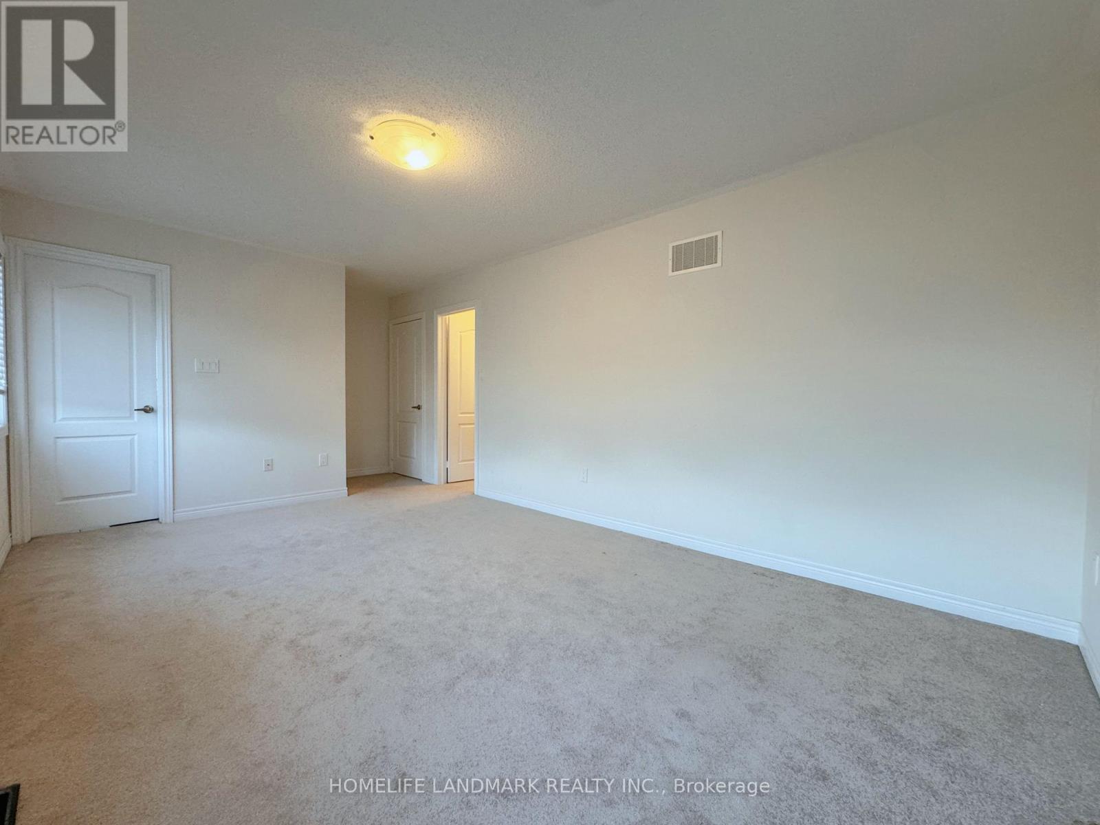 A spacious room with a carpeted floor and white walls.