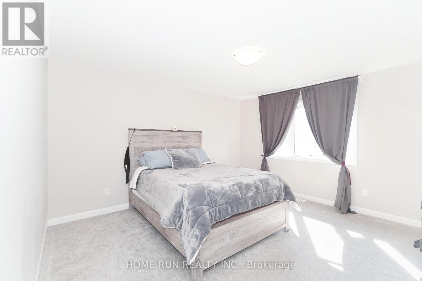 A bedroom with a large bed and a window with curtains.