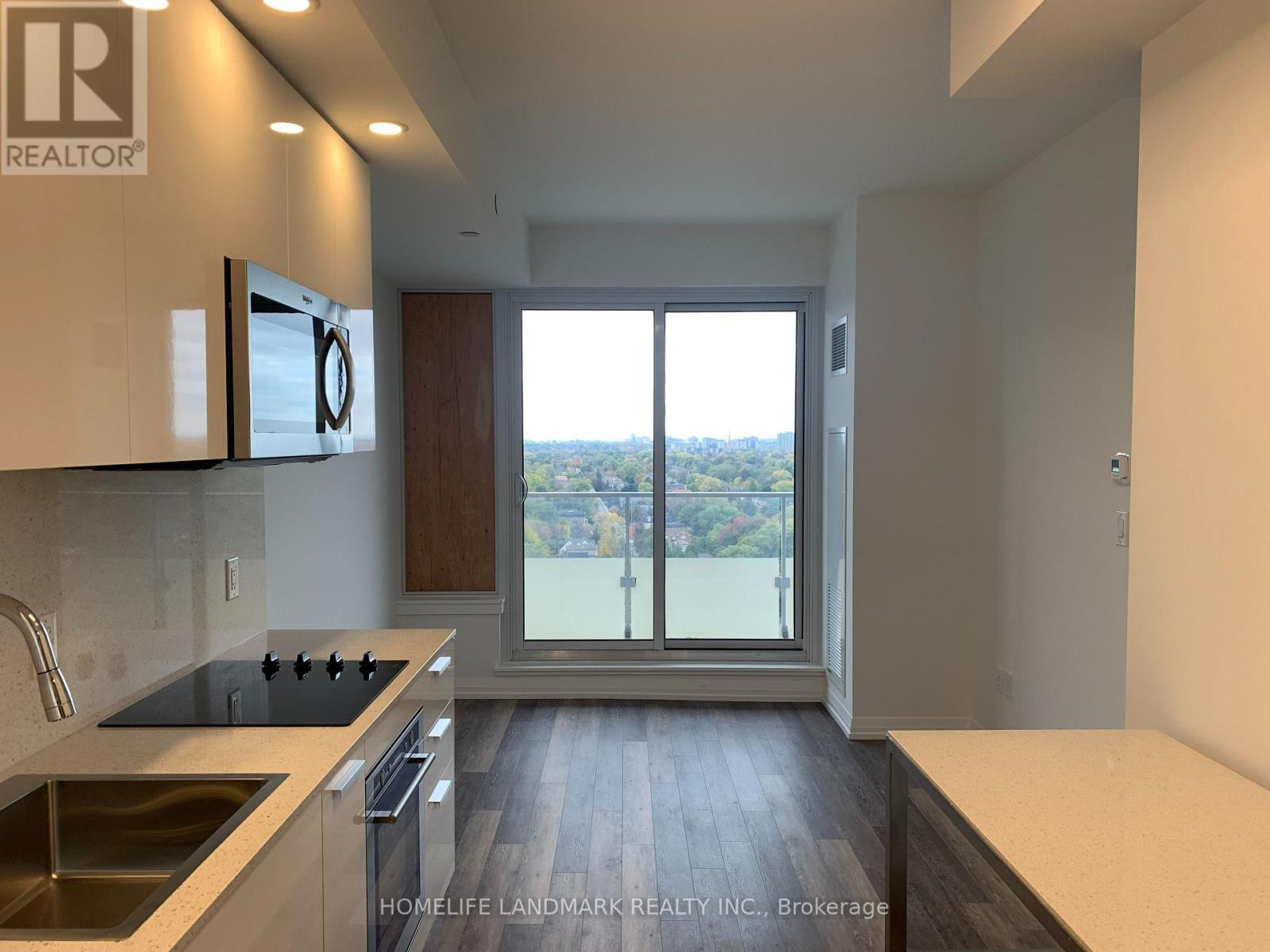 A modern kitchen with a view of the city through the sliding glass doors.