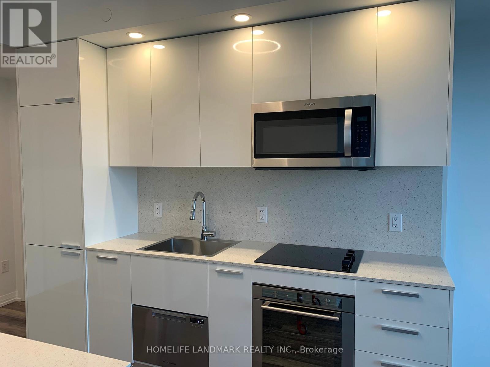 A kitchen with white cabinets and a black microwave.