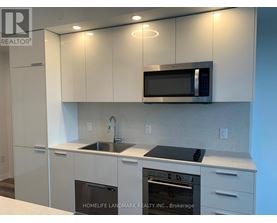 A kitchen with white cabinets and a black microwave.