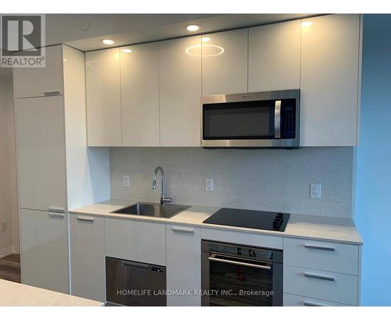 A kitchen with white cabinets and a black microwave.