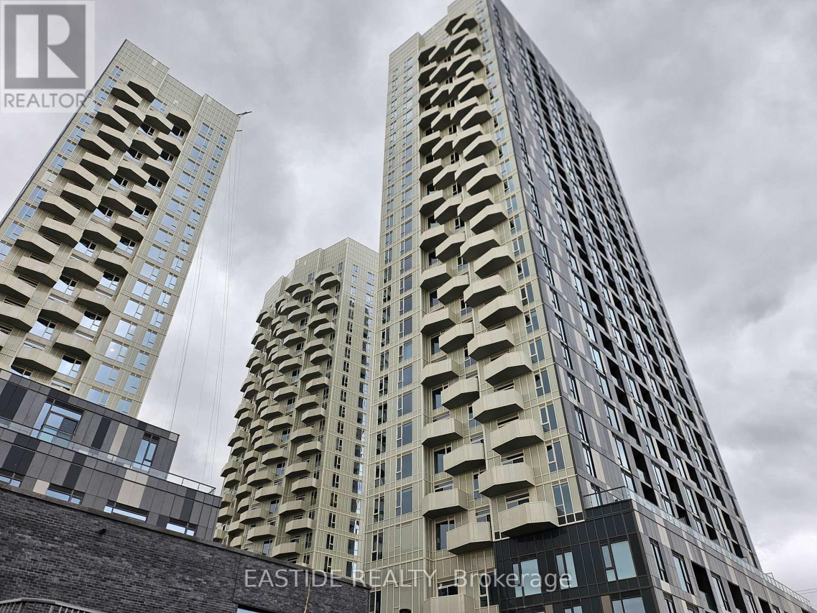 Two buildings with balconies in front of a cloudy sky.