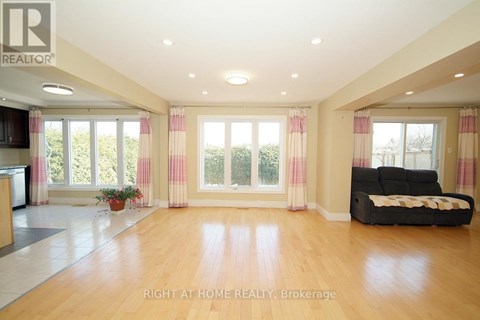A spacious living room with a black couch and wooden floors.
