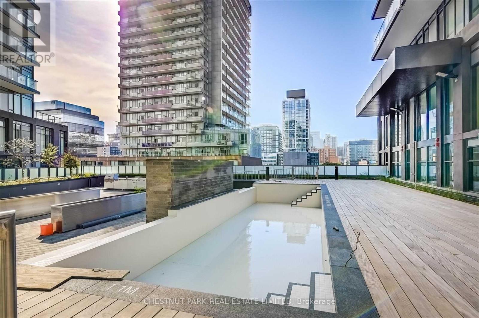 A rooftop pool area with a cityscape in the background.