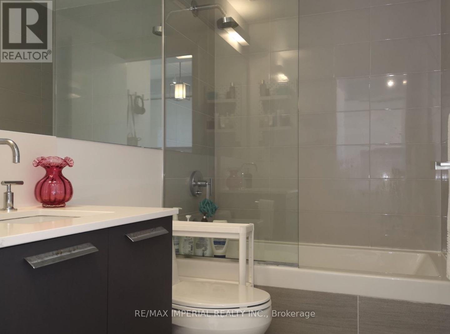 A bathroom with a glass shower stall and a white toilet.
