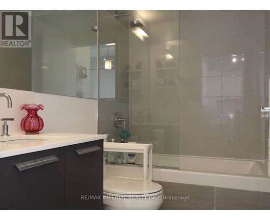 A bathroom with a glass shower stall and a white toilet.