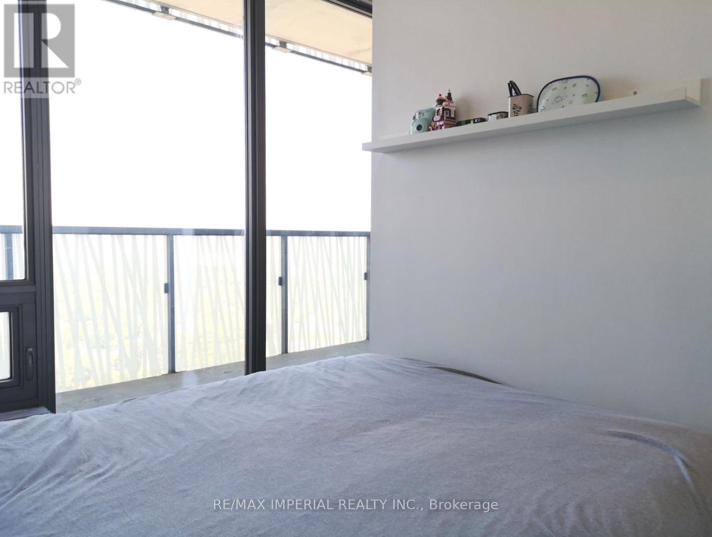 A bedroom with a bed, a shelf with decorative items, and a balcony with a railing.