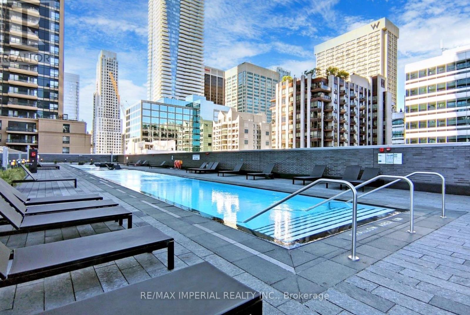 A pool surrounded by a metal railing and lounge chairs.
