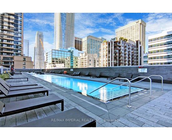 A pool surrounded by a metal railing and lounge chairs.