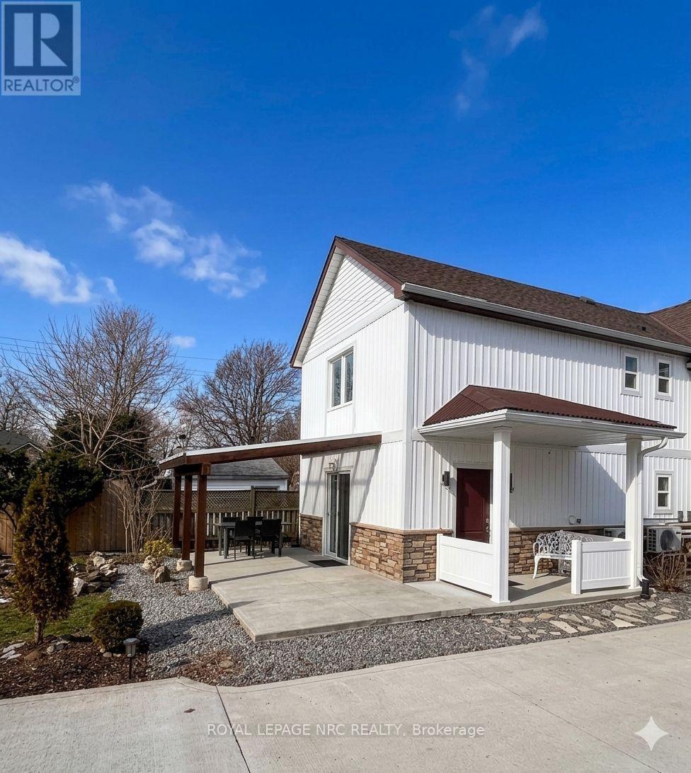 A white house with a brown roof and a covered patio area.