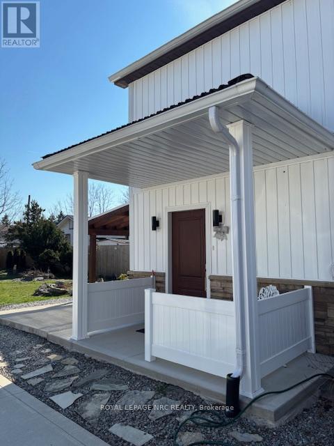A white porch with a brown door and a white railing.