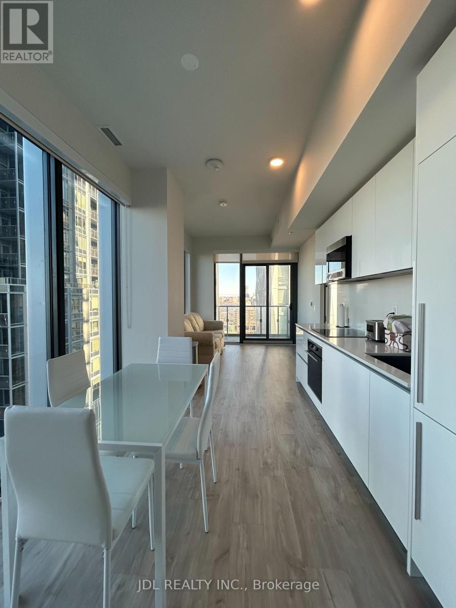 A modern kitchen with white chairs and a glass table.
