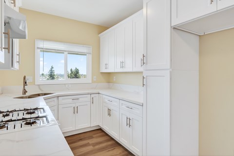 A kitchen with white cabinets and a white gas stove.