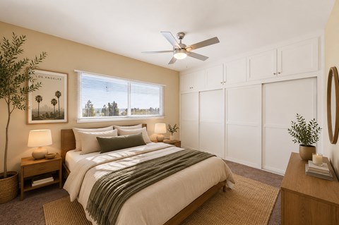 A bedroom with a bed, a ceiling fan, and a window with a view of palm trees.