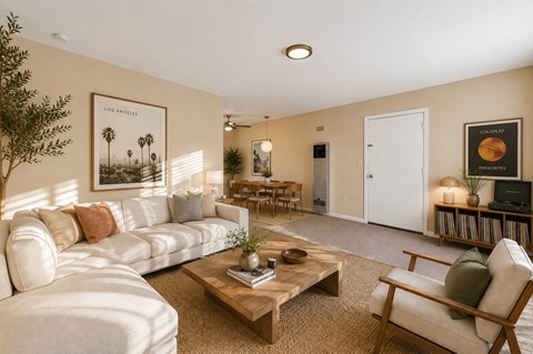 A living room with a white sofa, a wooden coffee table, and a painting of palm trees.