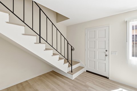 A white door is in a room with a staircase.
