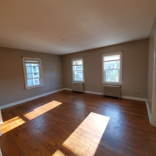 A room with wooden floors and three windows.