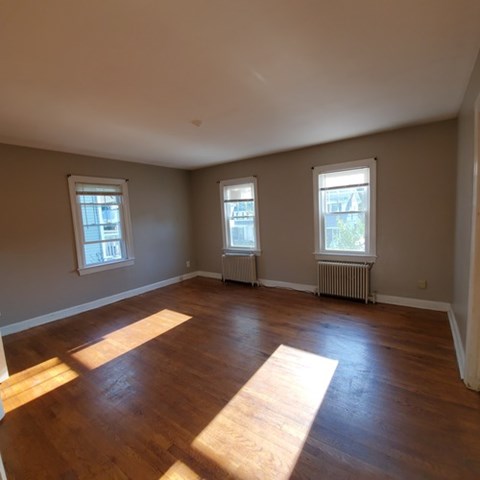 A room with wooden floors and three windows.