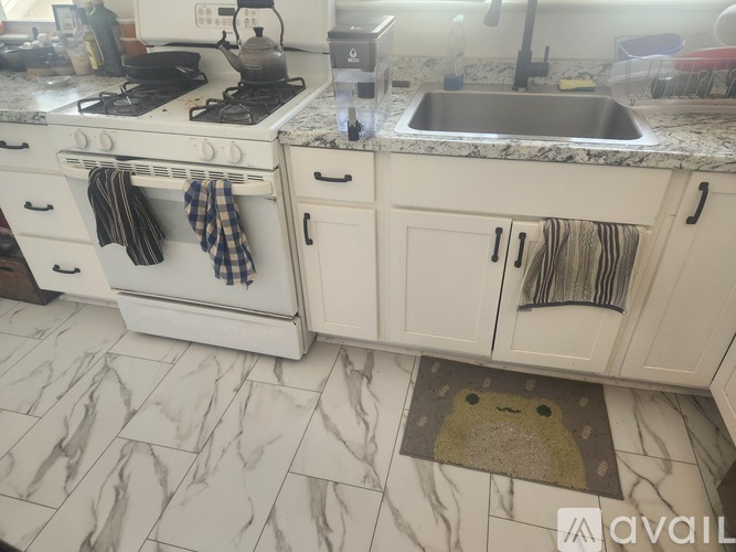 A kitchen with a white stove and white cabinets.