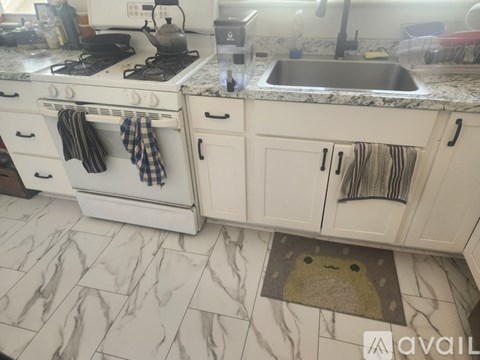 A kitchen with a white stove and white cabinets.
