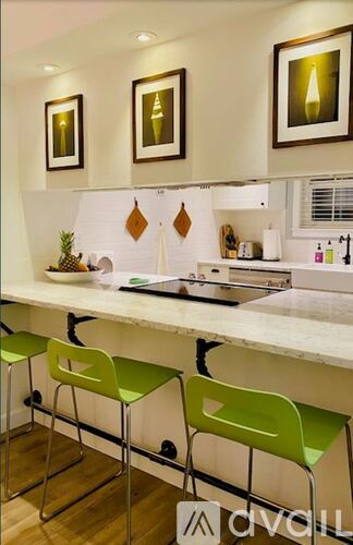 A kitchen with a white counter top and green chairs.