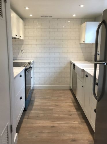 A kitchen with white cabinets and a white fridge.