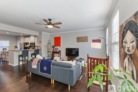 A living room with a grey couch and a ceiling fan.
